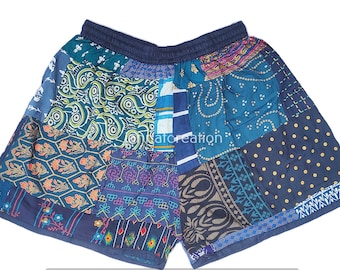 May include: Patchwork shorts in shades of blue, teal, and navy. The shorts feature a variety of patterned fabric patches, including paisley, floral, and geometric designs. The waistband is elasticized. A unique and colorful garment.