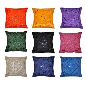 Puede incluir: Un conjunto de nueve fundas de coj&iacute;n cuadradas en naranja, amarillo, morado, verde, negro, rosa, beige, azul oscuro y azul claro. Cada funda presenta bordados intrincados y peque&ntilde;os espejos circulares en un patr&oacute;n de diamante con el texto JANNATCREATION.