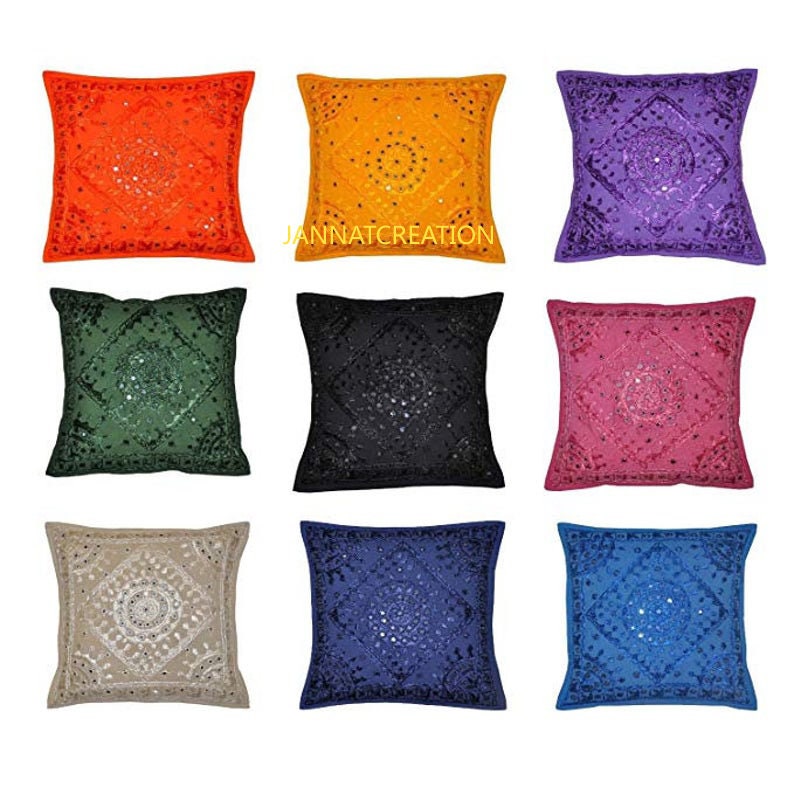 Puede incluir: Un conjunto de nueve fundas de coj&iacute;n cuadradas en naranja, amarillo, morado, verde, negro, rosa, beige, azul oscuro y azul claro. Cada funda presenta bordados intrincados y peque&ntilde;os espejos circulares en un patr&oacute;n de diamante con el texto JANNATCREATION.