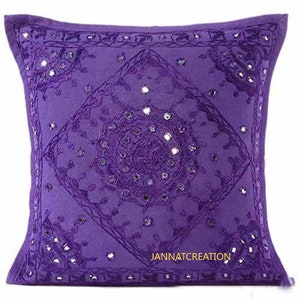 Puede incluir: Una funda de coj&iacute;n cuadrada de color morado con intrincados bordados en tonos a juego y peque&ntilde;os espejos circulares incrustados en la tela. El dise&ntilde;o incluye un patr&oacute;n de diamante central con motivos circulares y el texto JANNATCREATION.
