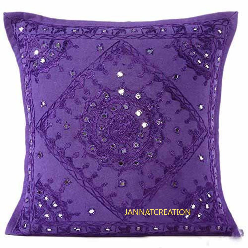 Puede incluir: Una funda de coj&iacute;n cuadrada de color morado con intrincados bordados en tonos a juego y peque&ntilde;os espejos circulares incrustados en la tela. El dise&ntilde;o incluye un patr&oacute;n de diamante central con motivos circulares y el texto JANNATCREATION.