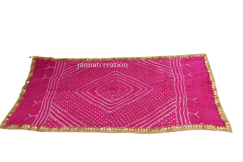 May include: A vibrant pink scarf with a geometric white pattern and a gold-colored border. The scarf has a rectangular shape and is likely made of a soft fabric. The text "jannatcreation" is visible on the scarf.