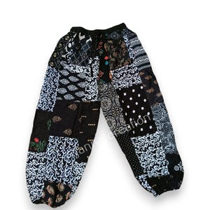 May include: Patchwork pants with a black background and various patterns in white, black, and other colors. The pants have a drawstring waist and a relaxed fit. The fabric appears to be lightweight.