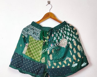 May include: Green patchwork shorts with a drawstring waist. The shorts are made of different fabrics with various patterns, including paisley, polka dots, and floral designs. The text "janmaicreator" is visible on the shorts.