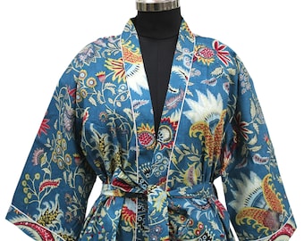 Puede incluir: Bata de color turquesa con estampado floral en rojo, amarillo y blanco. La bata tiene un ribete blanco y un cinturón a juego. La tela ligera sugiere su uso como bata de casa o prenda de abrigo.