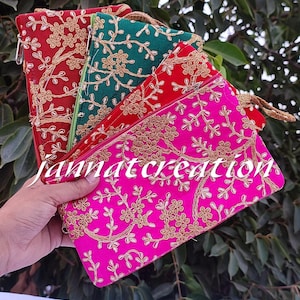 Può includere: Set di quattro pochette ricamate in rosa, rosso, verde e oro. Le pochette hanno un design floreale e sono perfette per trasportare piccoli oggetti.