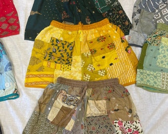 May include: A collection of patchwork shorts in various colors and patterns. The shorts feature a mix of floral, geometric, and abstract designs. Colors include yellow, green, brown, and red. The shorts have elastic waistbands and drawstring closures.