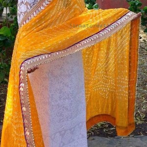 May include: A vibrant yellow saree with a detailed border. The saree features a dotted pattern and a decorative border with gold, red, and white accents. The text "jannatcreation" is visible on the fabric.