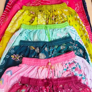 May include: A stack of eight colourful skirts with different patterns and designs. The skirts are made of cotton and have a drawstring waist. The skirts are all different lengths, ranging from short to long. The skirts are all in a variety of colours, including red, green, blue, pink, and yellow.