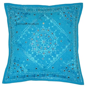 Puede incluir: Una funda de coj&iacute;n cuadrada de color turquesa con intrincados bordados tonales y peque&ntilde;os espejos circulares incrustados en la tela. El dise&ntilde;o incluye un patr&oacute;n de diamante central con motivos florales y el texto Jannatcreation.