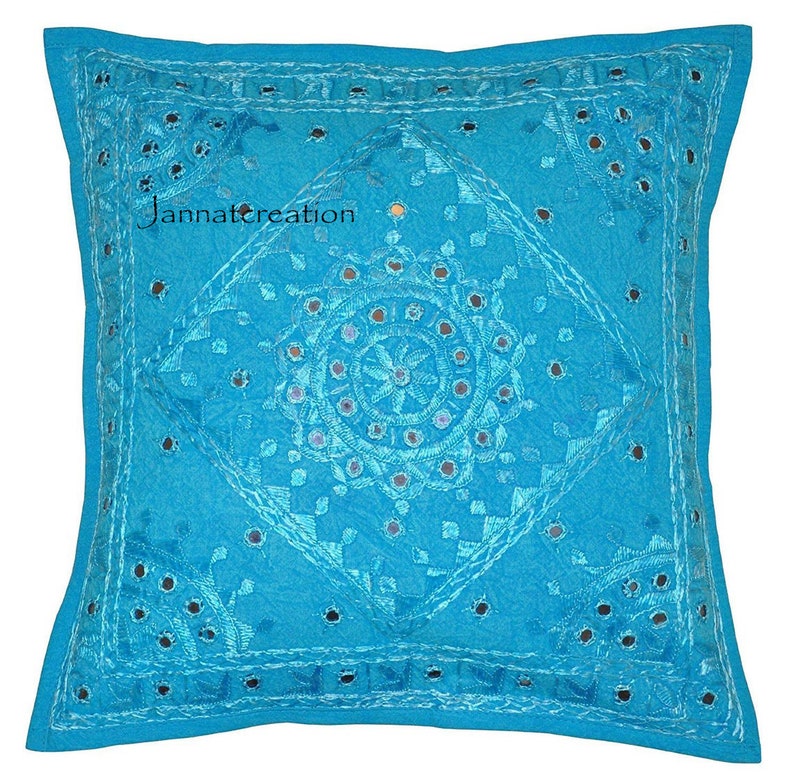 Puede incluir: Una funda de coj&iacute;n cuadrada de color turquesa con intrincados bordados tonales y peque&ntilde;os espejos circulares incrustados en la tela. El dise&ntilde;o incluye un patr&oacute;n de diamante central con motivos florales y el texto Jannatcreation.