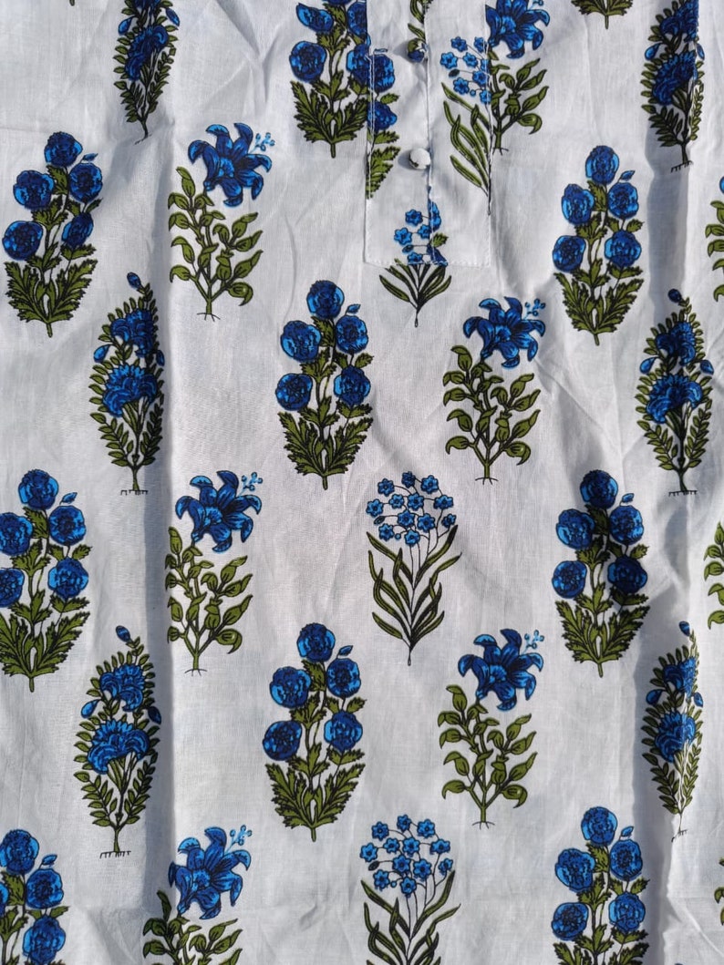 Puede incluir: Tela blanca con estampado floral azul y verde. La tela tiene un patr&oacute;n repetitivo de flores azules y hojas verdes.
