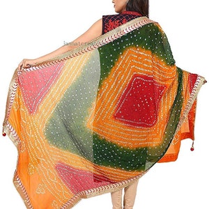 May include: A colorful, patterned scarf with a vibrant design. The scarf features a mix of orange, green, red, and pink hues, with a detailed border. The scarf is held open, showcasing its intricate patterns and textures.