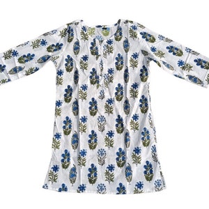 Puede incluir: T&uacute;nica de algod&oacute;n blanco con estampado floral azul y verde. La t&uacute;nica tiene un escote redondo y mangas tres cuartos.