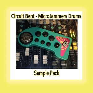 May include: A teal, boomerang-shaped electronic drum controller with a circular speaker grille, six black circular buttons, and a pink triangular graphic featuring the text Micro Jammers. The device is positioned over a black audio mixing console.