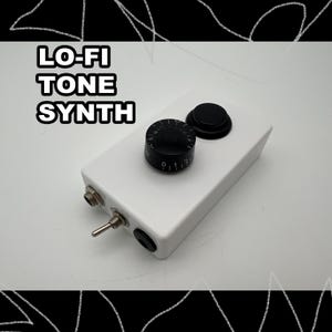 May include: A white rectangular electronic device labeled LO-FI TONE SYNTH featuring a black rotary knob with numbered markings from 0 to 10, a black circular push button, a metal toggle switch, and two circular input ports on the side panel.