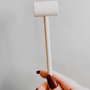 K&ouml;nnte beinhalten: Ein wei&szlig;er Holzhammer mit einem abgerundeten Kopf und einem langen, schlanken Stiel.