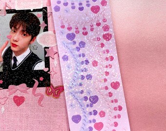 May include: A sheet of holographic stickers with a pink and purple gradient. The stickers feature a repeating pattern of hearts, chains, and bows.