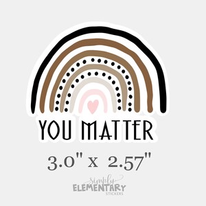 May include: A sticker with a rainbow in shades of brown, black, and white with a small pink heart in the center. The text "YOU MATTER" is below the rainbow and the size "3.0" x 2.57" is below the text. The text "simply ELEMENTARY STICKERS" is below the size.