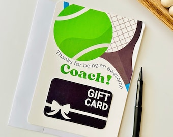 Può includere: Un biglietto bianco con una palla da tennis verde e un design di racchetta da tennis. Il biglietto dice "Grazie per essere un allenatore fantastico!" e ha una carta regalo nera allegata.