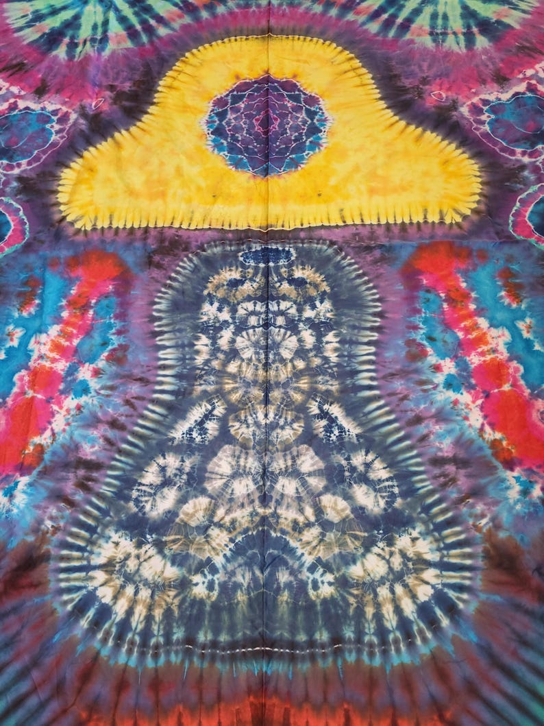 May include: A vibrant tie-dye textile featuring a symmetrical design with a large yellow shape at the top. The pattern incorporates shades of blue, purple, red, and brown, creating a psychedelic and artistic aesthetic. The fabric appears to be cotton or a similar material.