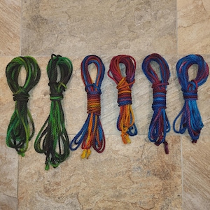 May include: Six different colored ropes, each tied in a loop. The ropes are green, orange, red, blue, and purple.