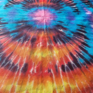 May include: A circular tie-dye pattern in shades of blue, red, orange, and yellow. The fabric has a textured, woven appearance.