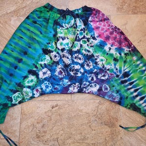 May include: Tie-dye pants with a blue, green, and pink color scheme. The pants have a wide leg and a drawstring waist.