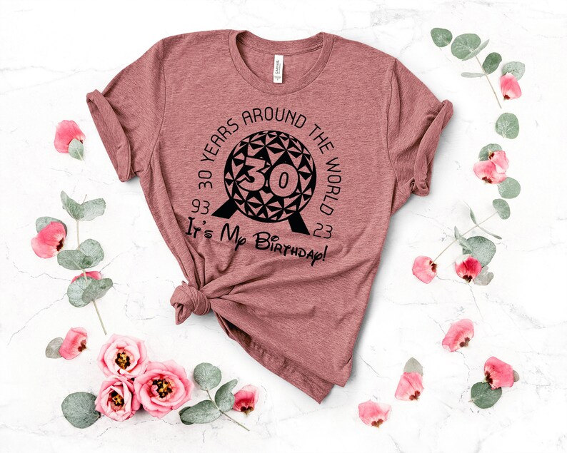 May include: A maroon t-shirt with a black graphic of the Epcot ball and the text "30 Years Around The World 93-23 It's My Birthday!"