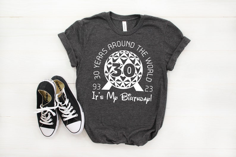 May include: A dark gray t-shirt with a white graphic design featuring the Epcot Spaceship Earth icon and the text "30 Years Around The World 93 - 23 It's My Birthday!"