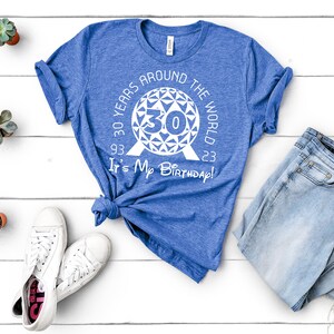 May include: A blue t-shirt with a white graphic of the Epcot Spaceship Earth with the text "30 Years Around The World 93 30 23 It's My Birthday!"
