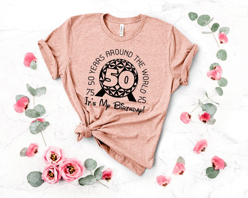 May include: A pink t-shirt with a black graphic design of a sphere with the number 50 inside. The text around the sphere reads "50 Years Around The World 75 25 It's My Birthday!"