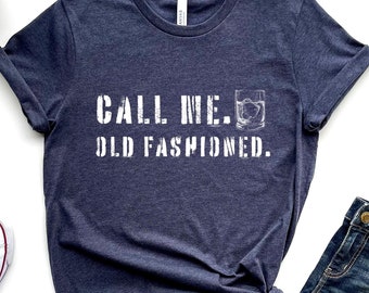May include: A navy blue t-shirt with white text that reads "Call me. Old Fashioned." and a graphic of a glass of whiskey with ice.