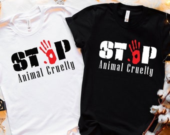 Könnte beinhalten: Zwei T-Shirts mit dem Aufdruck "STOP Animal Cruelty". Ein T-Shirt ist weiß und das andere schwarz. Beide T-Shirts haben ein rotes Handabdruck-Motiv.