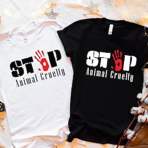 May include: Two t-shirts with the text "STOP Animal Cruelty" printed on them. One t-shirt is white and the other is black. Both t-shirts have a red handprint graphic.