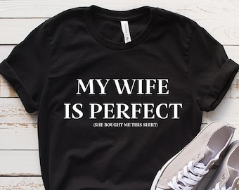 May include: Black t-shirt with white text that reads "My wife is perfect (she bought me this shirt)".