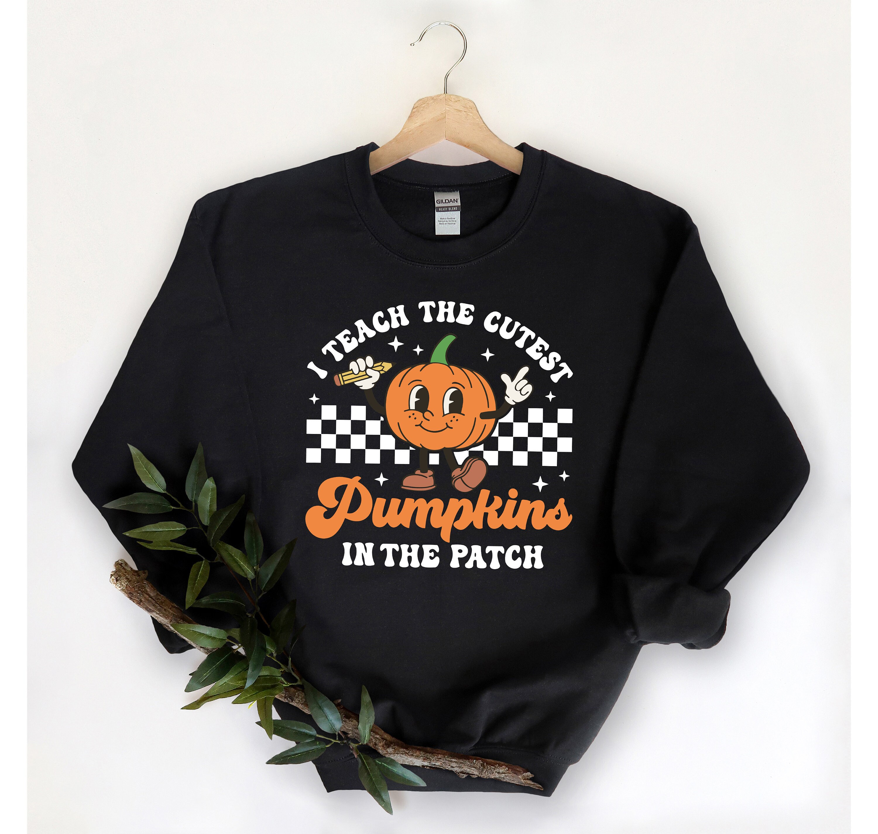 May include: Black sweatshirt with a white and orange graphic of a pumpkin holding a pencil and a peace sign. The text reads "I teach the cutest pumpkins in the patch".