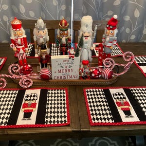 May include: A table setting with a Christmas theme featuring nutcracker figurines, candy canes, and a sign that reads "Have yourself a merry little Christmas".