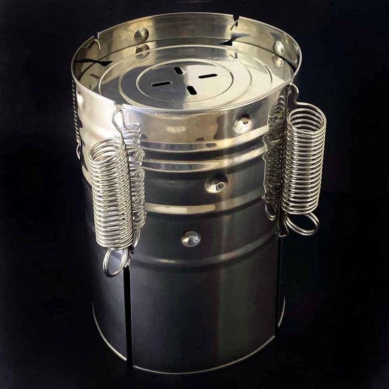 May include: A silver metal container with a lid and two spring-loaded handles. The container has a textured surface and appears to be made of stainless steel.