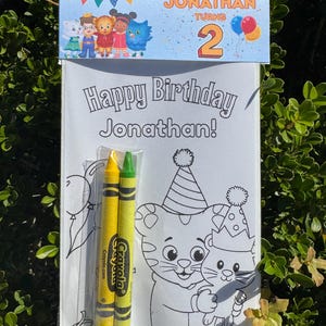 May include: A birthday coloring book set for Jonathan, featuring Daniel Tiger characters. The set includes a coloring book with the text "Happy Birthday Jonathan!" and two crayons. The top banner reads "Jonathan Turns 2".