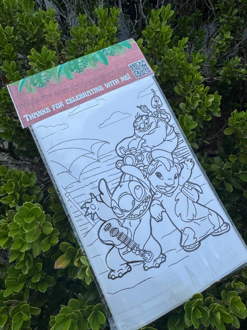 May include: A clear plastic bag containing a black and white coloring page featuring cartoon characters. The top of the bag has a brown and green design with the text "THANKS FOR CELEBRATING WITH ME!" and a QR code.