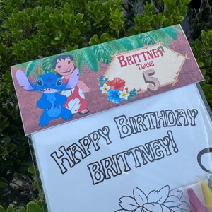 May include: A clear plastic bag containing a coloring book and crayons. The coloring book has the words "Happy Birthday Brittney!" printed on it. The top of the bag has a decorative banner with the words "Brittney Turns 5" and images of Stitch and Lilo.