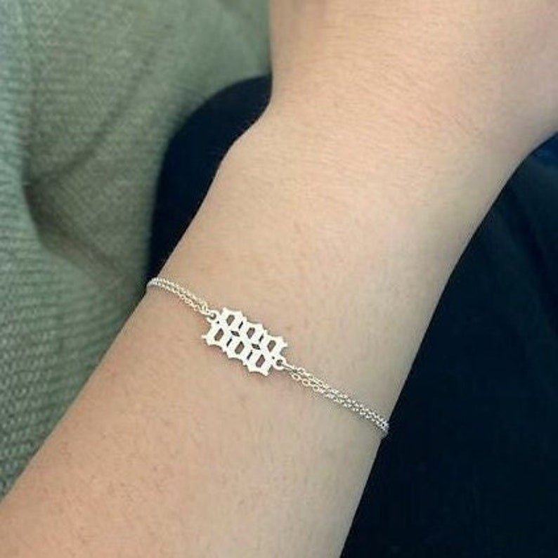 May include: A silver chain bracelet with a silver charm that says "666" in a gothic font.