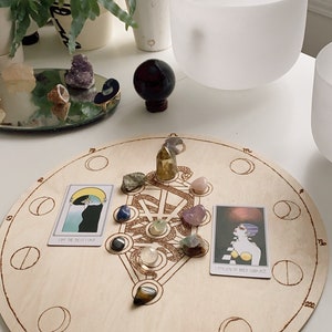 May include: A wooden moon phase board with a tree of life design and crystals. The board has a circle for each moon phase and the zodiac signs around the edge. The cards say "I Did The Best I Could" and "I Follow My Heart's Guidance".
