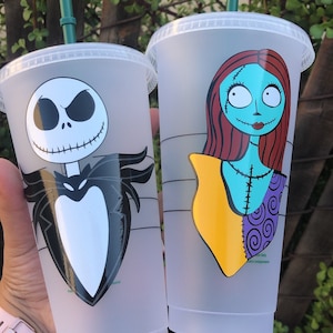 May include: Two clear plastic cups with green lids and straws. The cups have images of Jack Skellington and Sally from the Nightmare Before Christmas.