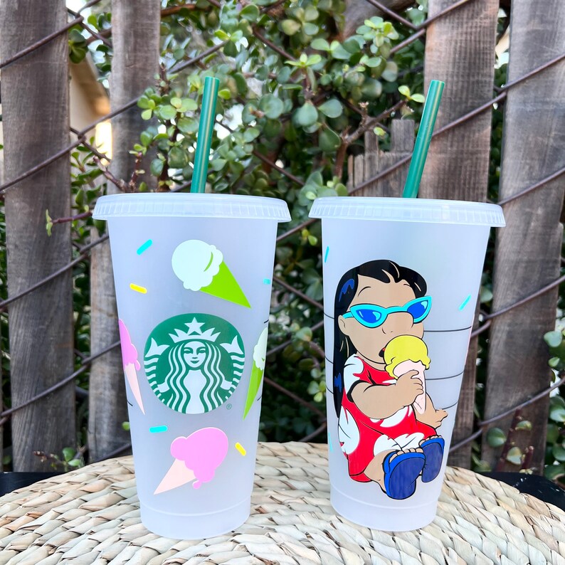 May include: Two clear plastic reusable cups with lids and straws. One cup has a design of a cartoon character with a yellow ice cream cone. The other cup has a design of ice cream cones and the Starbucks logo.