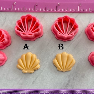 May include: A set of six pink plastic shell-shaped cookie cutters, with two larger cutters and four smaller cutters. There are also two yellow shell-shaped cookie cutters.