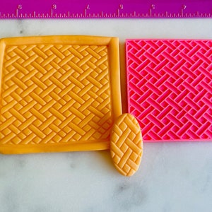 May include: Three silicone baking mats with a woven pattern. The mats are yellow, pink, and orange. The mats are on a white surface.