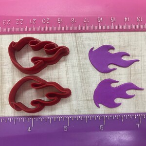 May include: Two red plastic cookie cutters shaped like flames, and two purple fondant flames.