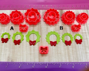 May include: Set of red and green plastic cookie cutters shaped like wreaths with bows. The cutters are arranged in two rows, labeled A and B.